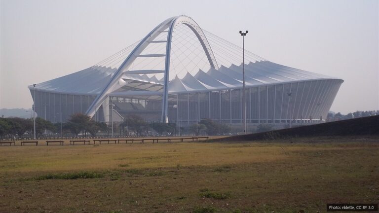 Durban Olympic Bid: Why Durban Was Picked for 2036 or 2040 and What Happens Next Moses Mabhida Stadium in Durban with its white arch, seen across an open grass field on a hazy day