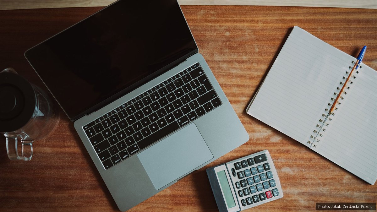 EMP501 Interim Reconciliation 2026: Deadline 31 October, What to Check and How to Submit A laptop, a desk calculator and an open notebook with a pen on a wooden desk, seen from above