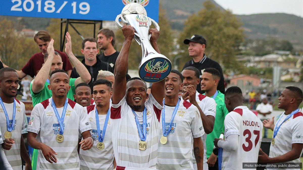 Stellenbosch FC players in white and maroon kit celebrate with medals as Angelo Kerspuy lifts the 2018/19 National First Division trophy